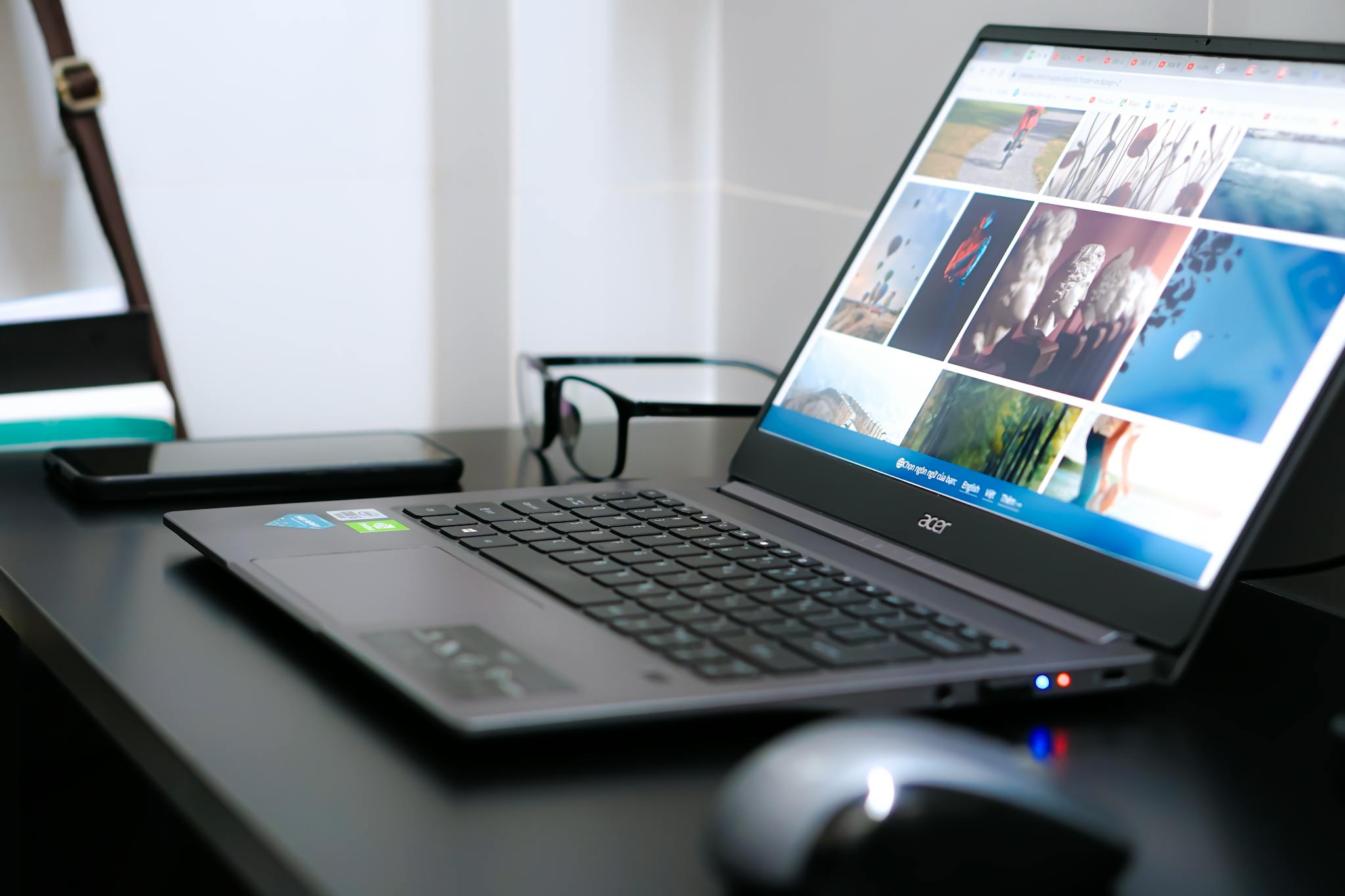 A sleek laptop on a desk with glasses and mouse, ideal for tech or business themes.